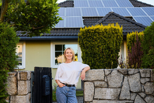 Person standing outside house with solar panels on the roof