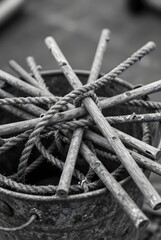 Dark Still Life of Wooden Sticks and Rope in Metal Bucket