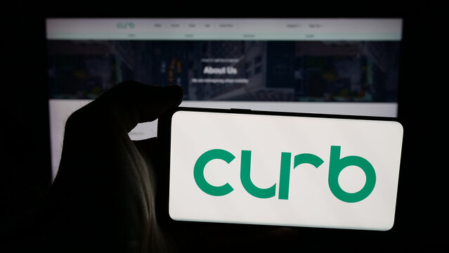 Stuttgart, Germany - 02-02-2026: Person holding mobile phone with logo of US taxi app company Curb Mobility LLC on screen in front of web page. Focus on phone display.