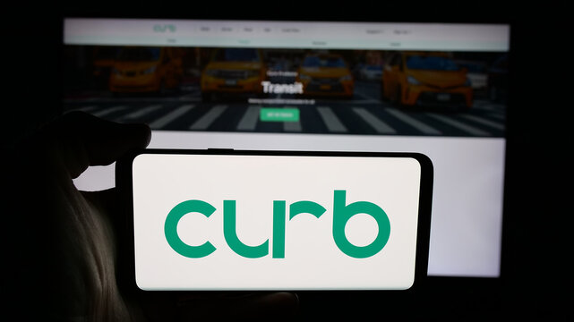 Stuttgart, Germany - 02-02-2026: Person holding cellphone with logo of US taxi app company Curb Mobility LLC on screen in front of webpage. Focus on phone display.