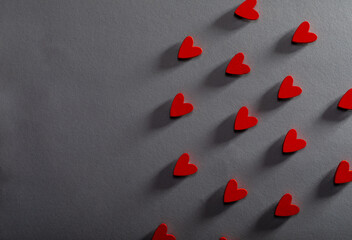 Overhead view of red heart shaped decorations arranged over gray background with copy space