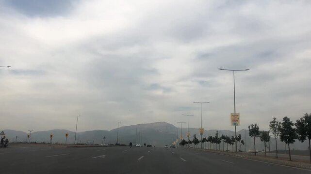 Wide-angle driving footage captured on Margalla Road in Islamabad, Pakistan. The scene features a smooth urban road, streetlights, light traffic, and distant Margalla Hills under a clear sky. 