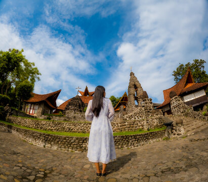 An Asian woman is alone in the poh sarang church. The church has stone walls.
