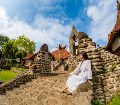 An Asian woman is alone in the poh sarang church. The church has stone walls.