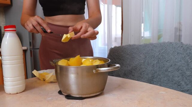 Home Cook Pouring Milk Into Stainless Pot Filled With Peeled Potatoes, Plastic Milk Bottle Beside Pot, Counter Kitchen Setting, Preparing Creamy Mashed Potatoes, Stirring And Simmering