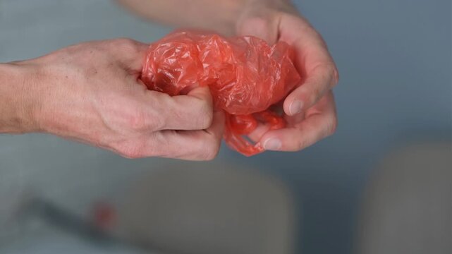 Men's hands are clutching a plastic bag.