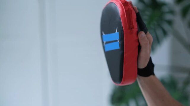 A close-up of a gloved punch hitting a boxing mitt. Kids boxing.