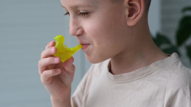A boy blows into a plastic bird filled with water, making bird sounds.

