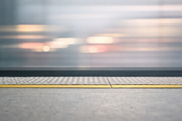 Platform edge with tactile paving at train station and blurred train motion
