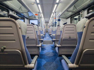 Fototapeta premium View of interior in a deserted empty commuter train railway carriage with rows of seats and tables
