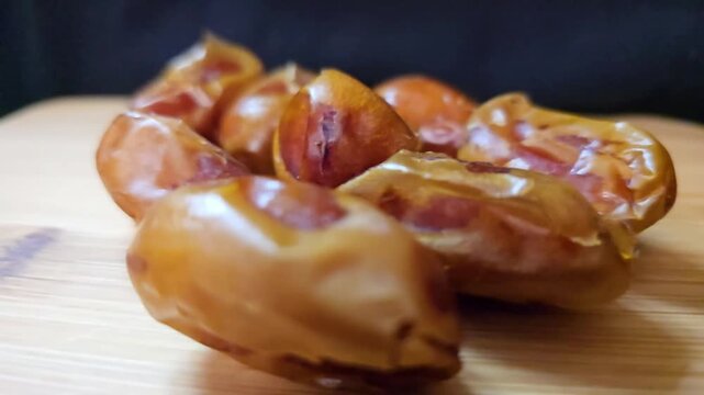 A high-quality macro video showcasing premium Saudi Khalas dates, capturing their natural sheen and rich caramel-colored skin.