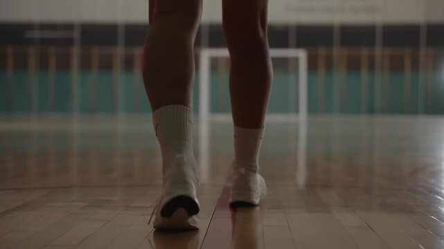 Back view of professional handball athlete running and throwing ball into empty net