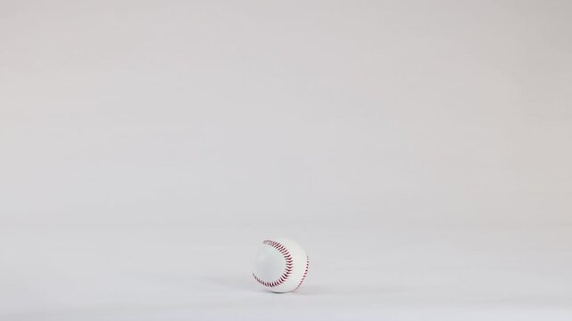 White Baseball with Red Stitching Bouncing on a Plain White Background