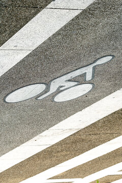 Bicycle symbol on bike lane asphalt with white stripe road marking for urban traffic and transport direction on textured pavement
