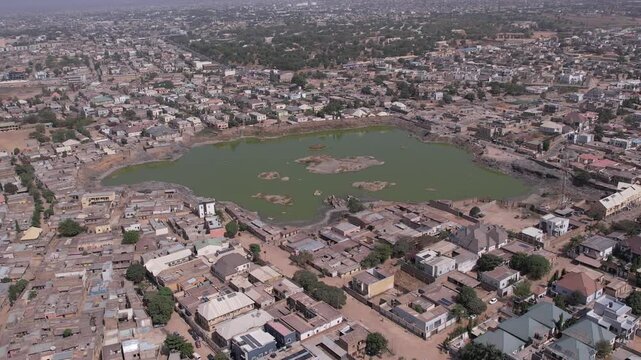Aerial view of a lake surrounded by buildings, revealing a mix of textures and tones across the landscape, Kano, Kano, Nigeria.