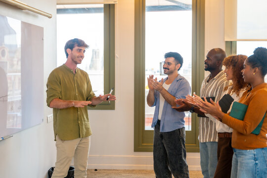 Business team applauding colleague giving presentation at modern office