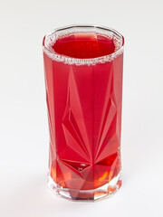 Vibrant red berry drink in a faceted glass tumbler, isolated on a clean white background. © Andrei Starostin