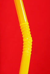 flexible drinking yellow straw on red background