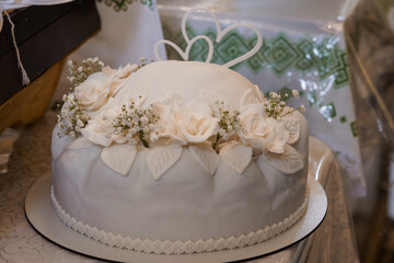 Elegant White Wedding Cake Decorated with Fresh Flowers and Heart Shaped Toppers on a Festive Table Setting