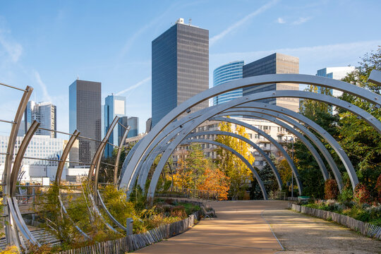 Perspective along a park walkway through arches toward a skyline in daylight autumn in Promenade de la Rose de Cherbourg Paris La Defense