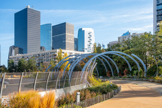 Arches line a park walkway with an urban skyline in daylight autumn in Promenade de la Rose de Cherbourg Paris La Defense modern