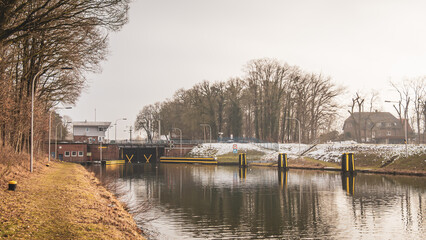 Obraz premium Osnabrück canal lock on the Stichkanal Osnabrück at the Mittellandkanal, calm water and lock infrastructure in winter sunlight, Germany