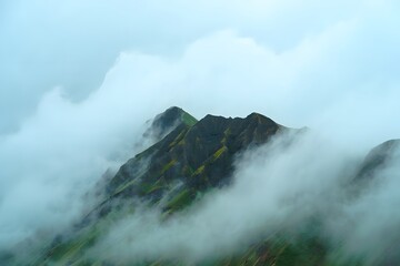 A rugged mountain peak rises above a blanket of misty clouds