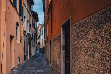 Obraz premium Characteristic narrow cobblestone alley overlooked by old Italian houses with traditional architecture. Italian cityscape, Udine, Friuli Venezia Giulia, Italy.