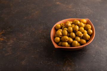 Fresh green olives in ceramic clay bowl on black concrete. side view
