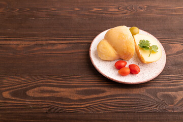 Smoked Mozzarella cheese, with tomatoes and olives on brown wooden, side view, copy space.