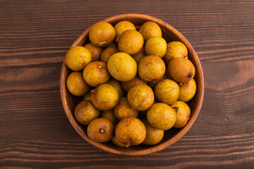 Ripe Longan in wooden bowl on brown wooden, Top view, flat lay, close up
