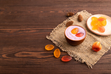 Purple Yogurt, with jelly candy on brown wooden and linen textile, side view, copy space