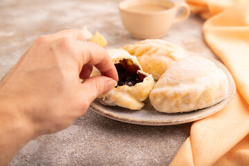 Glazed Pies with blueberry jam on brown concrete with hand, side view, close up, selective focus