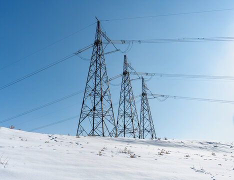 Soviet Era Power Transmission Towers in Snowy Uzbekistan under Clear Blue Sky