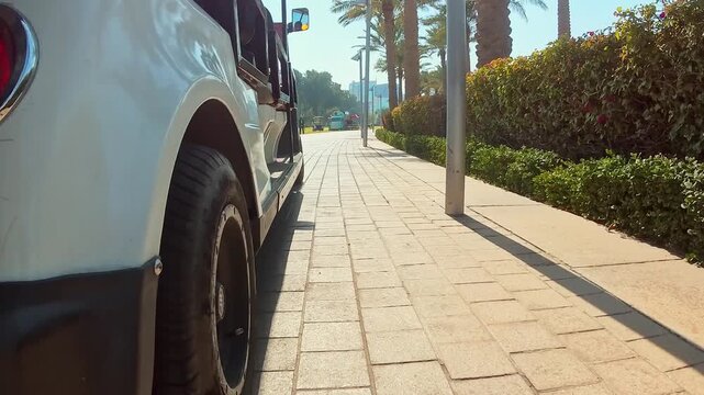 Doha, Qatar - 18th january, 2026: Electric tourist shuttle driving along Doha Corniche promenade with palm lined sidewalk urban mobility sustainable transport concept daytime travel scene