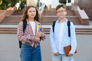 School children standing with backpacks and books outdoors
