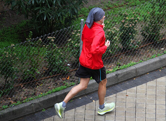 Runner corriendo y en carrera de footing con pa&ntilde;uelo sport por acera de calle