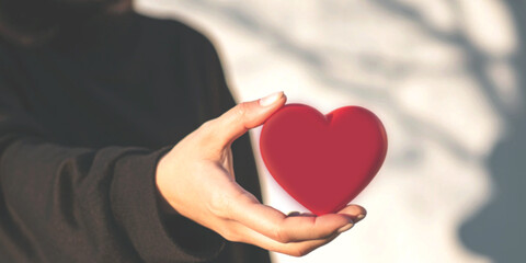 Person wearing black holding a red heart representing unrequited love and heartache