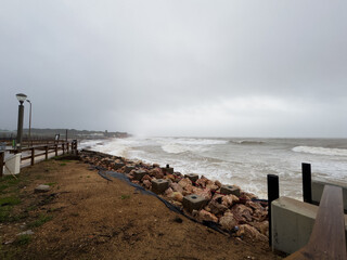 Dramatic Waves Crashing Against Rocky Beach Shore on a Cloudy Day.