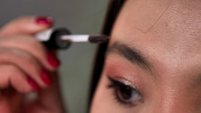 Woman Applying Eyeliner, Brow Gel, and Mascara Makeup
