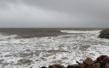 Dramatic Waves Crashing Against Rocky Beach Shore on a Cloudy Day.