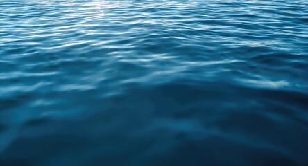 Fototapeta premium Blue water surface with blurred ripples and sunlight highlights for use as copy space background