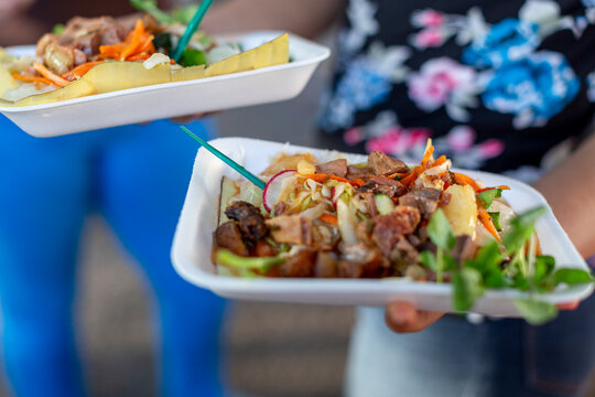 Salvadoran street food yuca con chicharr&oacute;n (fried cassava with pork) in takeaway trays at a street market in Santa Ana, El Salvador, topped with curtido (pickled cabbage slaw) and fresh vegetables.