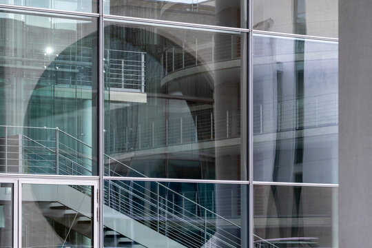 Glass facade architecture in Berlin Germany with reflection and staircase windows revealing modern interior layers inside an urban building
