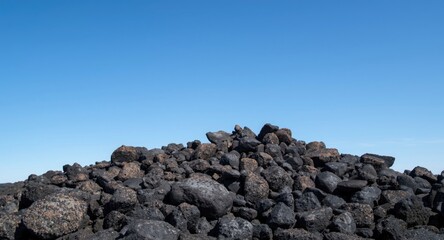 Cluster of dark volcanic stones with a pristine blue sky overhead