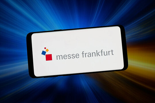 Stuttgart, Germany - 02-06-2026: In this photo illustration, the logo of trade fair company Messe Frankfurt GmbH is displayed on a smartphone in front of abstract background on computer screen.