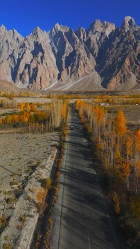 Aerial view of Passu Cones with a road cutting through, the landscape a mix of bare trees and autumn colors, Hunza Nagar, Pakistan.
