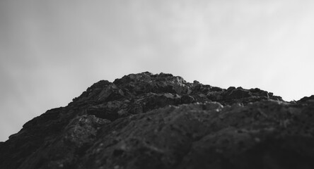 Grayscale artistic photo focusing on rock formation texture beneath clear sky