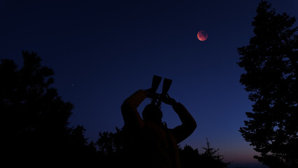 Fototapeta premium Amateur astronomer using binoculars for observing stars, planets, Moon and other celestial objects.