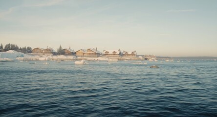 Obraz premium Frosty sea and comfortable chalets captured during a winter morning
